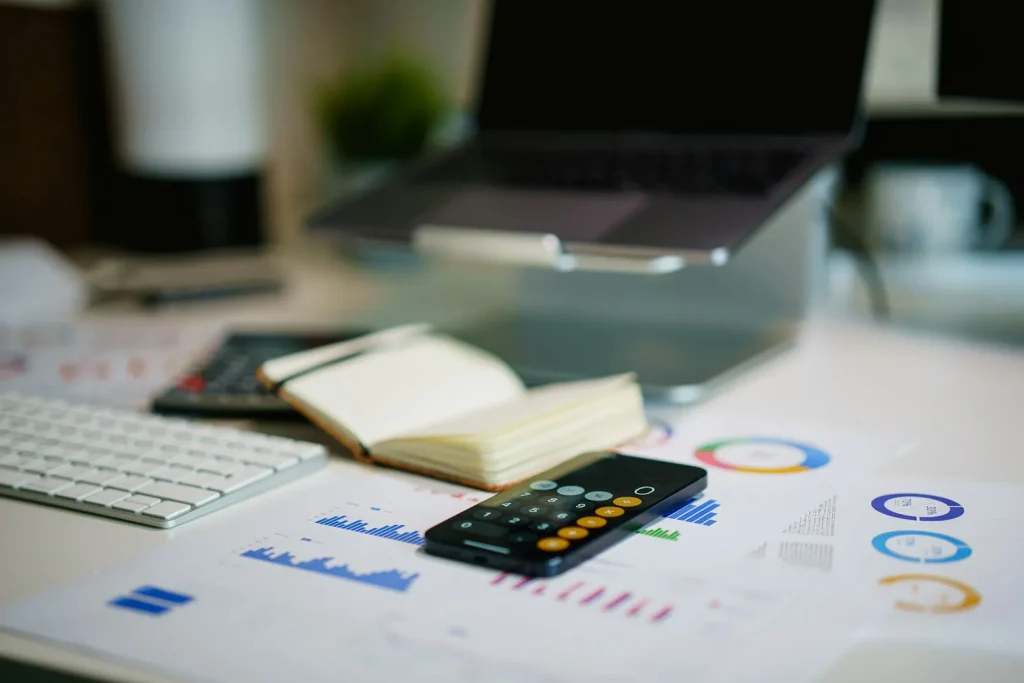 Office desk with financial charts and a smartphone representing bank reconciliation and payroll prep work