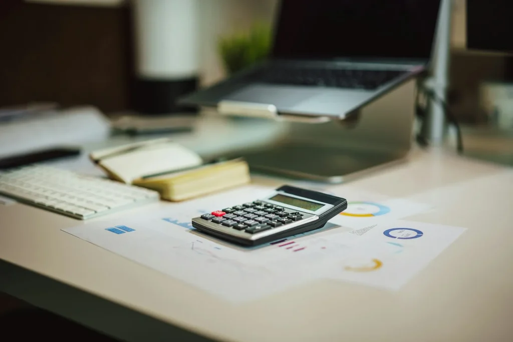 Calculator and financial documents representing the cost of outsourced back-office support for a UK accounting practice