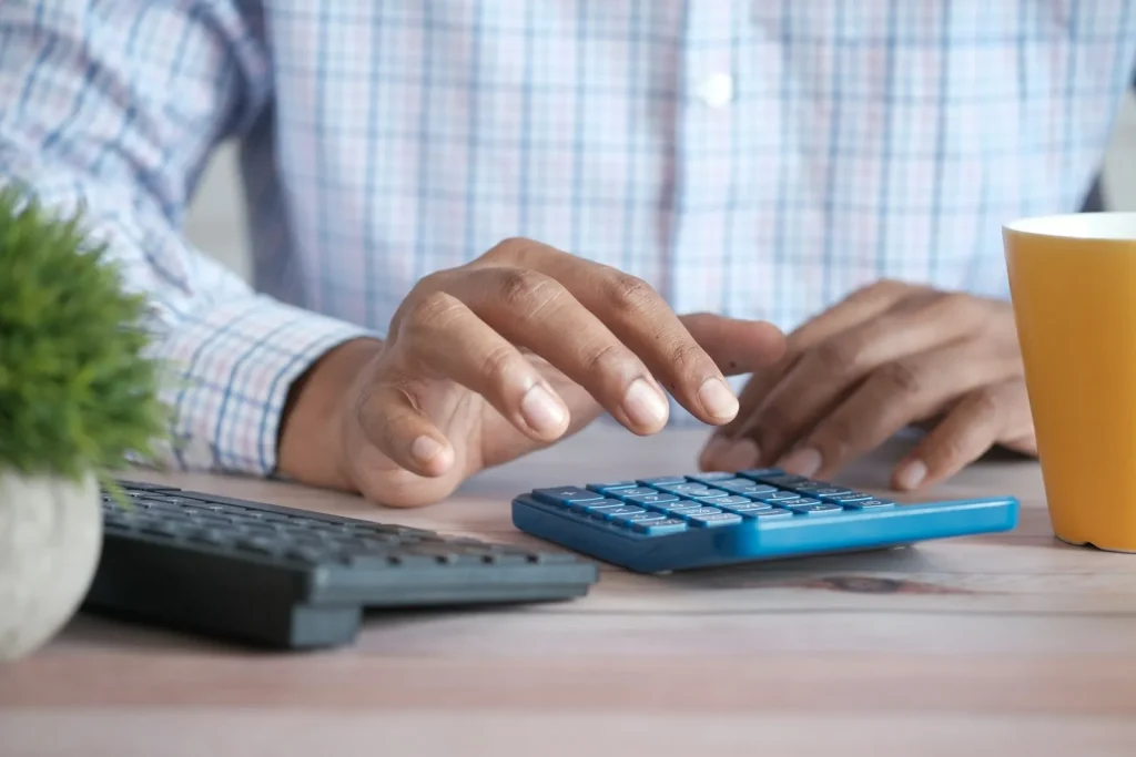 Accountant using a calculator during busy UK tax season while preparing SA100, CT600 and CGT returns